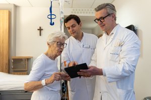 Zwei Ärzte erläutern einer Patientin die Behandlung mithilfe eines Tablets