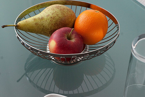 Ein Metallkorb mit einer Birne, einem Apfel, einer Orange