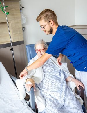 Pfleger richtet Infusion einer älteren Patientin