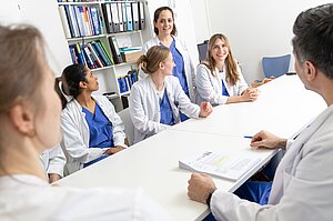 Am Tisch sitzen sechs Ärzte und Ärztinnen bei einer Fortbildung