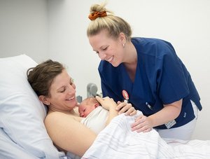 Mutter mit Neugeborenem und einer Mitarbeiterin